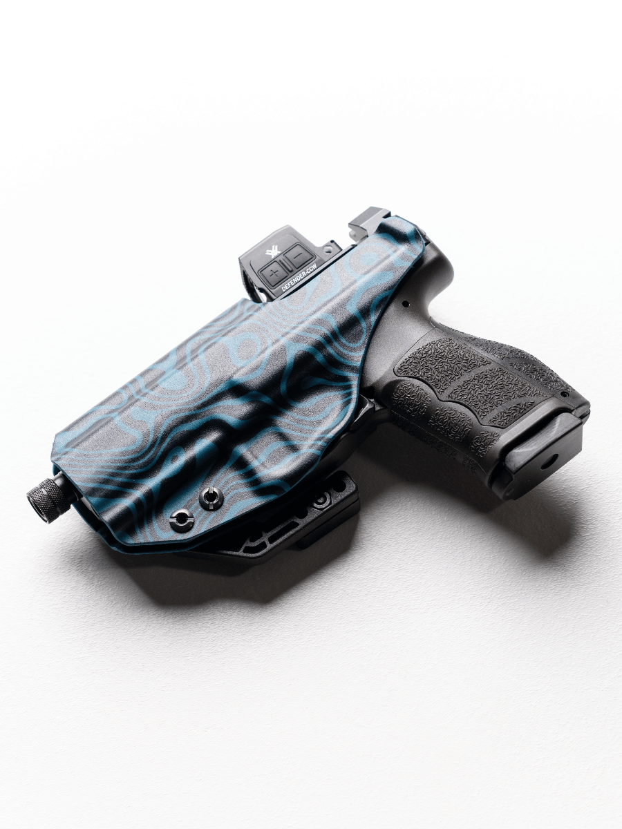 A black handgun in a custom blue and black patterned Kydex holster, photographed on a clean white background with a soft shadow.