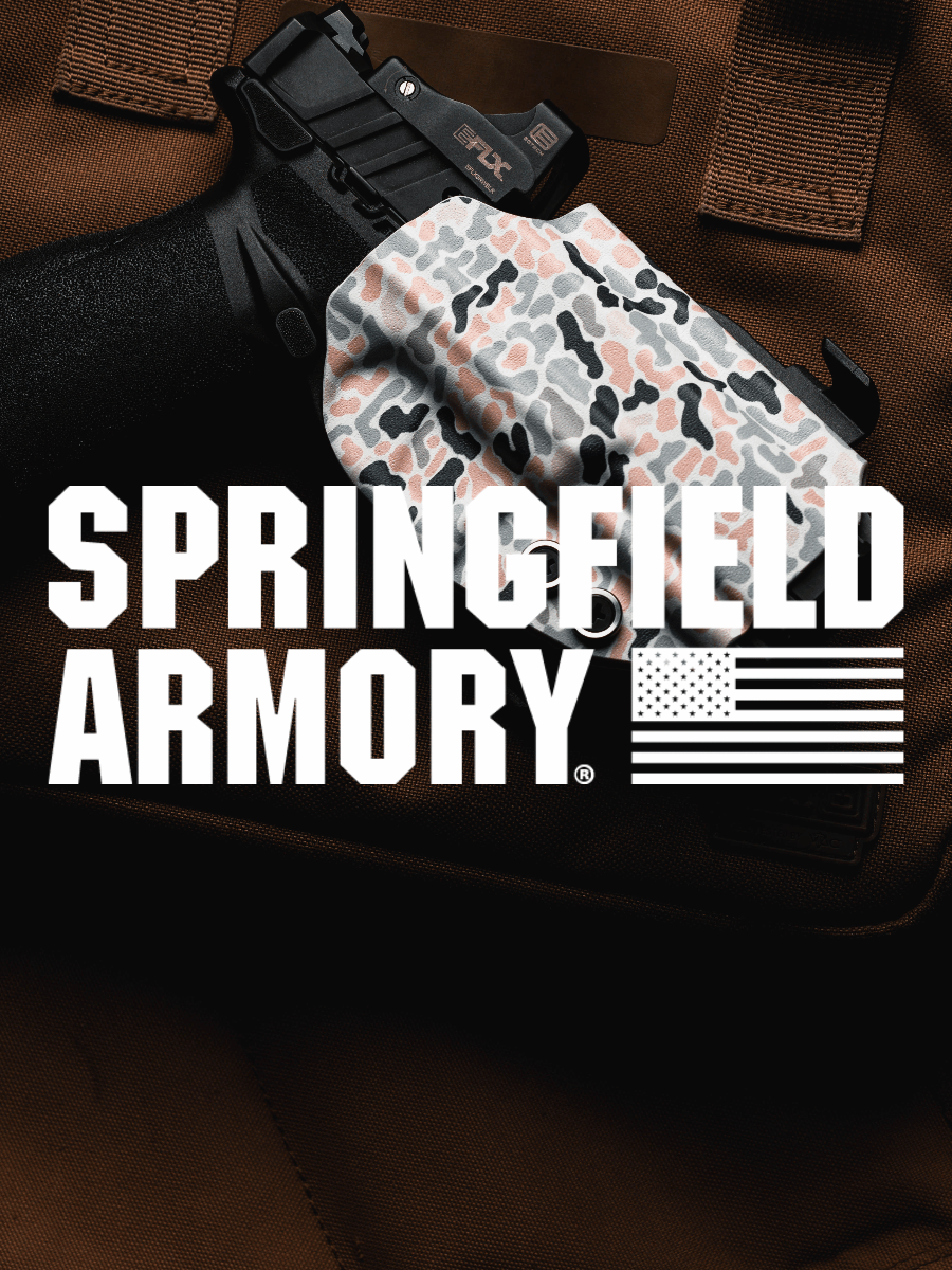 A handgun resting on a brown tactical vest, with a camouflage-patterned holster covering the grip. Large white text across the center reads 'SPRINGFIELD ARMORY' with a U.